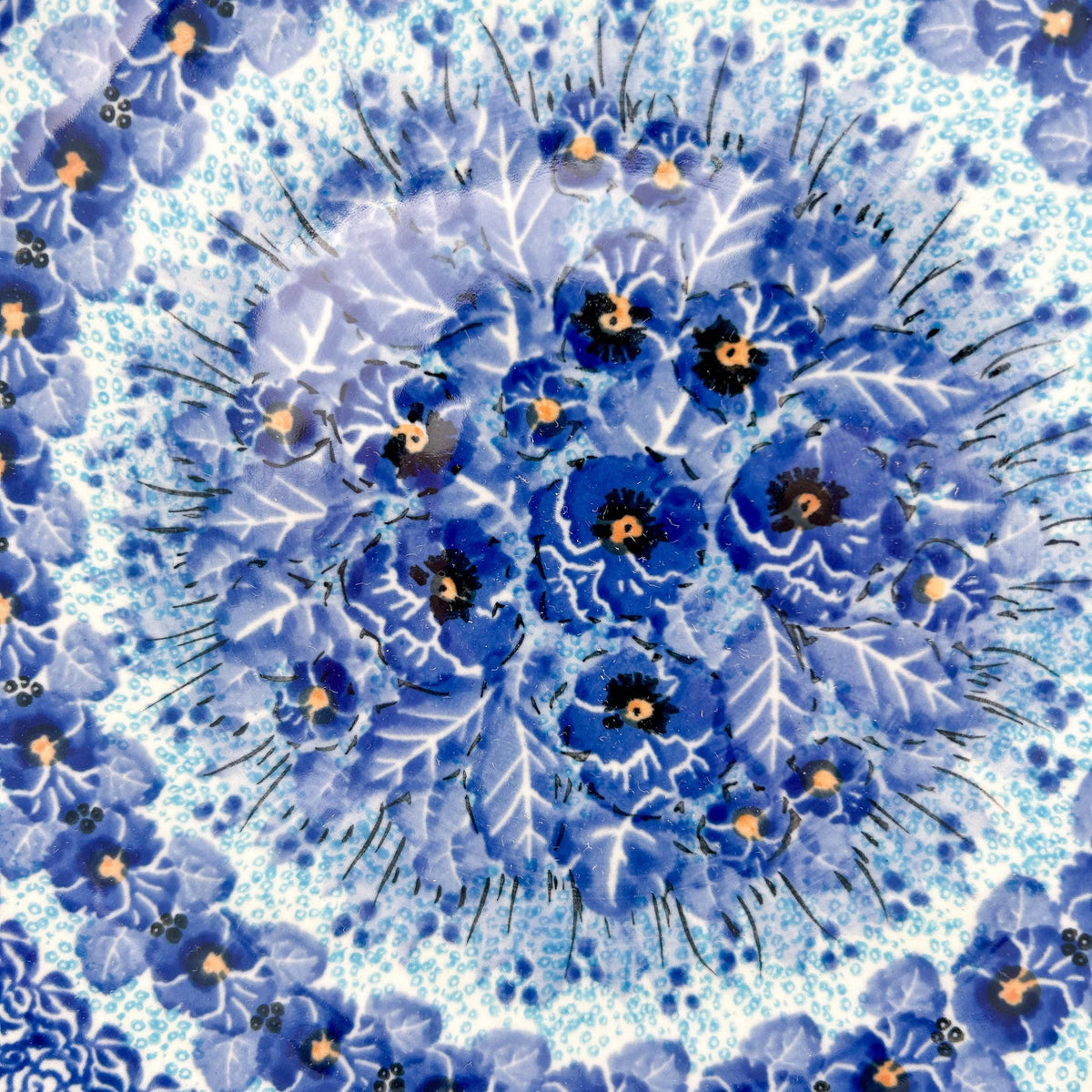 UNIKAT Deep Winter plate, close-up top-down view of blue pansy cluster center
