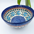Blue Cornflower deep bowl, angled top-down view with plant in background