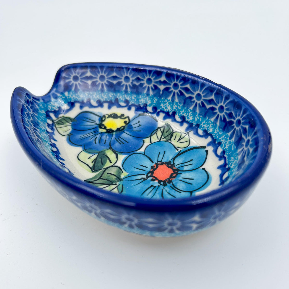 This 5” blue floral spoon rest is a handmade by talented Polish artisans. This is a Polish UNIKAT Bold Blue Poppies pattern 
Dimensions 5” x 3.54"
Ceramika BonaCompany