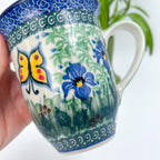 Close-up of butterfly and blue flower on Spring Garden bistro mug, held in hand