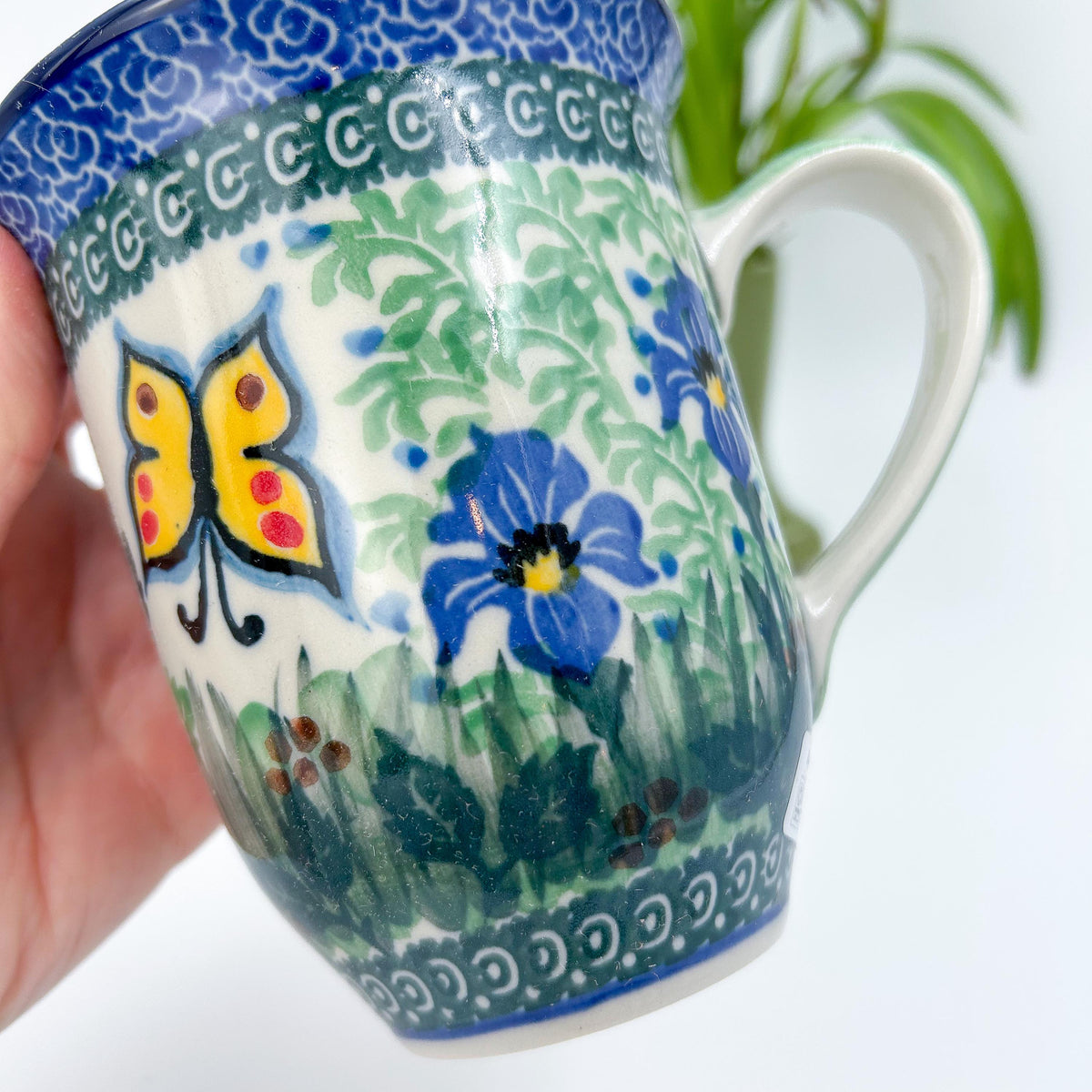 Close-up of butterfly and blue flower on Spring Garden bistro mug, held in hand